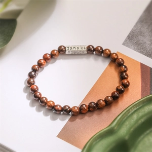 Détail d'un bracelet en perles de bois foncé de 6 mm avec tube en argent gravé