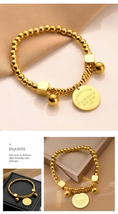 Detail of gold titanium steel bead bracelet with engraved eternal love disc and charms