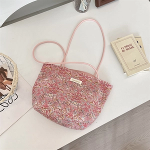 Vue à plat d'un sac cabas en toile à fleurs avec étiquette de marque sur un bureau