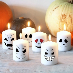 Set of 6 Halloween white pillar candles with diverse spooky skeleton face prints on wood