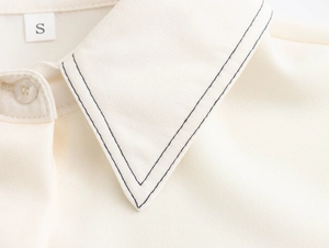 Detail of white shirt collar with black contrast stitching and size S label