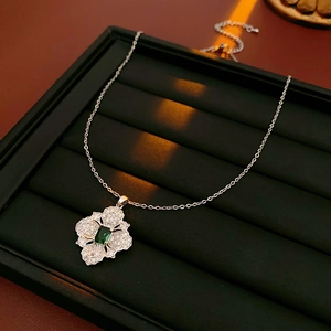 Detail of silver flower necklace featuring emerald green gemstone and sparkling zircons