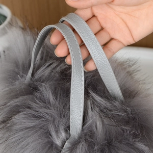 Dettaglio della borsa in pelliccia grigia con manico in pelle e trama morbida peluche