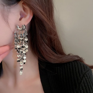 Close-up of long U-shaped silver sequin fringe earrings worn by a model