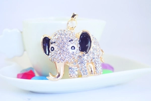 Detailed close-up of golden elephant keychain with crystals on a white heart tray