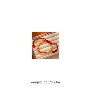 Detailed macro view of a red cord bracelet with gold coins on a beige velvet base