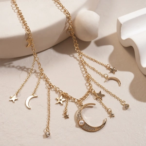 Détail du collier doré multicouche avec pendentif lune en strass et breloques étoiles