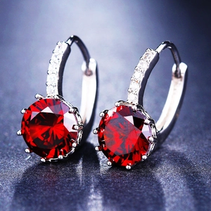Macro detail of silver hoop earrings featuring a large six-prong set red zircon and pave stones
