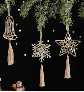 Close-up of golden Christmas ornaments with bells and tassels hanging on pine branches