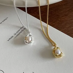 Macro detail of silver and gold irregular lava frame necklaces with white pearls