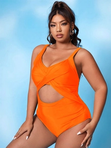 Detail of cross-wrap design and circular cutout on bright orange one-piece swimsuit