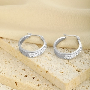 Close-up of double-row crystal inlaid silver stainless steel earrings on a stone plate