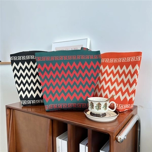 Three knitted tote bags featuring colorful zigzag patterns and Greek key border details
