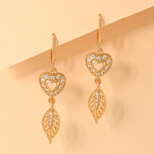 Detailed macro view of champagne gold leaf and heart-shaped earrings with white zircons
