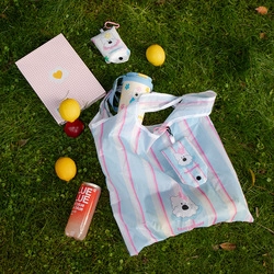 Detail of blue and pink striped portable shopping bag with white bear pattern on grass