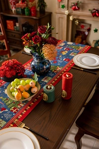 Detail of Christmas table runner with blue jacquard tree pattern and red tassels