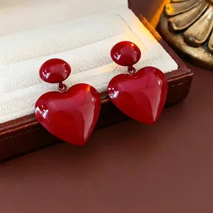Minimalist red heart pendant earrings with glossy finish on a jewelry box display