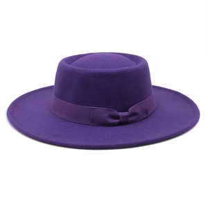 Detail of elegant dark purple wool felt boater hat with a ribbed ribbon bow on a white background