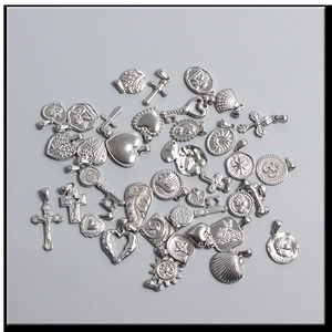 Macro shot of assorted silver vintage pendants including cross, heart, and sun shapes