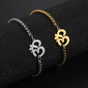Gold and silver Hindu OM symbol anklets with box chains on a dark display stand
