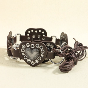 Detail view of brown faux leather belt with heart metal buckle and grommet eyelets