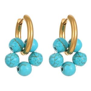 Close-up of gold hoop earrings with turquoise beads and natural brown stone textures