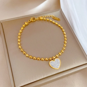 Polished gold beaded bracelet with a sparkling crystal heart charm in a premium gift box