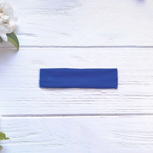 Détail d'un bandeau de yoga bleu marine élastique sur un fond en bois blanc
