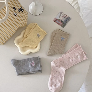Flat lay of colorful speckled knit socks with cute bow embroidery in soft autumn tones