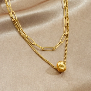 Double-layered gold chain necklace with geometric round bead pendant on silk background