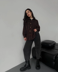 Full body view of women's red and black plaid shirt with charcoal jeans and black boots