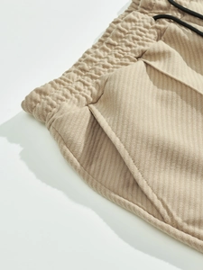 Dettaglio di pantaloni jogger kaki con trama a coste, vita elastica e coulisse nera