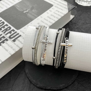 Close-up of bohemian layered leather bracelet with Blessed cross charm and rhinestones