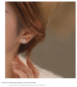 Macro shot of polished S925 silver bow earrings with sparkling cubic zirconia on ear