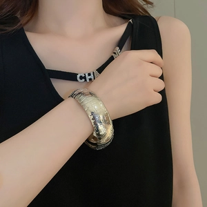 Macro detail of silver-finish metal cuff bracelet with realistic crocodile skin texture