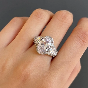 Macro-opname van halo-ring met ovale zirkoon en baguette-stenen aan de vinger