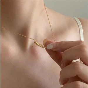 Close-up of a 925 sterling silver gold-plated bow necklace on a female collarbone