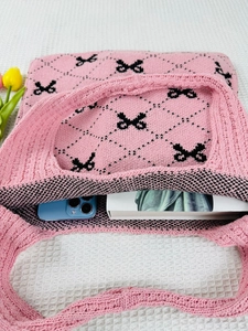 Detailed top view of pink knitted tote bag with black bow pattern and spacious interior