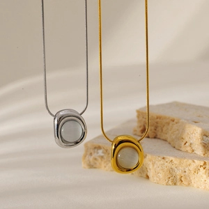 Detail of silver and gold snake bone necklaces with white cat eye stone pendants