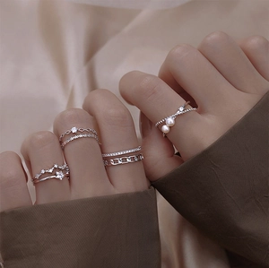 Detail of layered silver rings set with star, pearl and zirconia on model hand