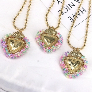 Detail of candy-colored beaded heart necklaces with golden mirrors on white cloth