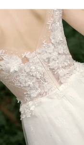 Detail of bridal dress featuring 3D floral lace embroidery and pearl beads on ivory tulle
