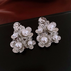 Macro detail of silver flower earrings with hammered texture and center white pearls