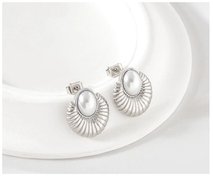 Detail of silver oval pearl earrings featuring ribbed shell texture on a white tray