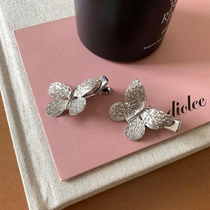 Elegant silver butterfly hair clips with textured metal wings on a pink card base