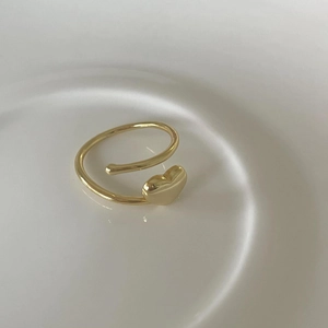 Minimalist golden 925 sterling silver heart open ring on a white ceramic tray