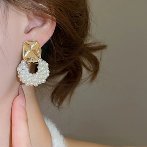 Close-up of elegant woven pearl hoop earrings with embossed gold square stud for women