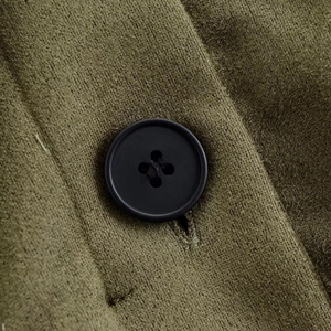 Detailed macro shot of olive green suede fabric texture with a black four-hole button