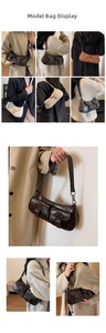 Close-up of vintage faux leather crescent bag showing dual pocket detail and metal buckles