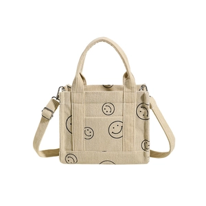 Beige corduroy tote bag with black smile print and adjustable shoulder straps on white background
